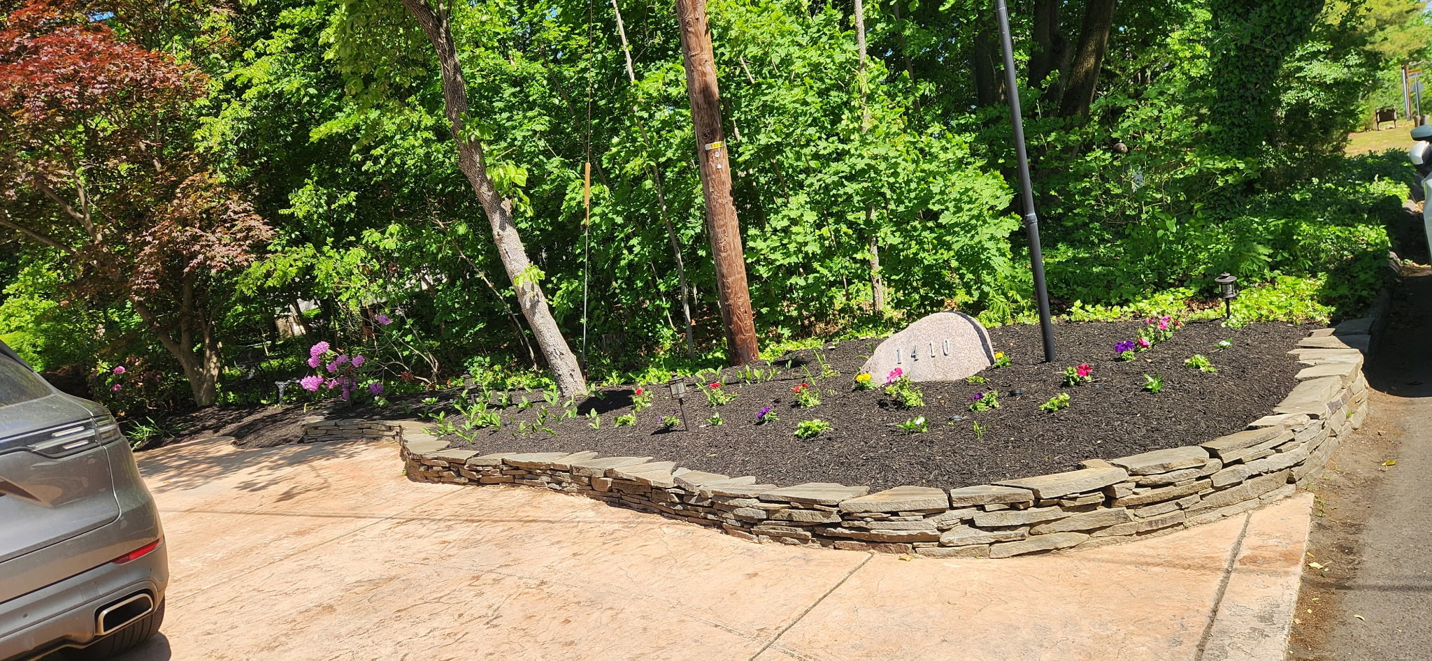 Stacked natural stone retaining wall with flower bed