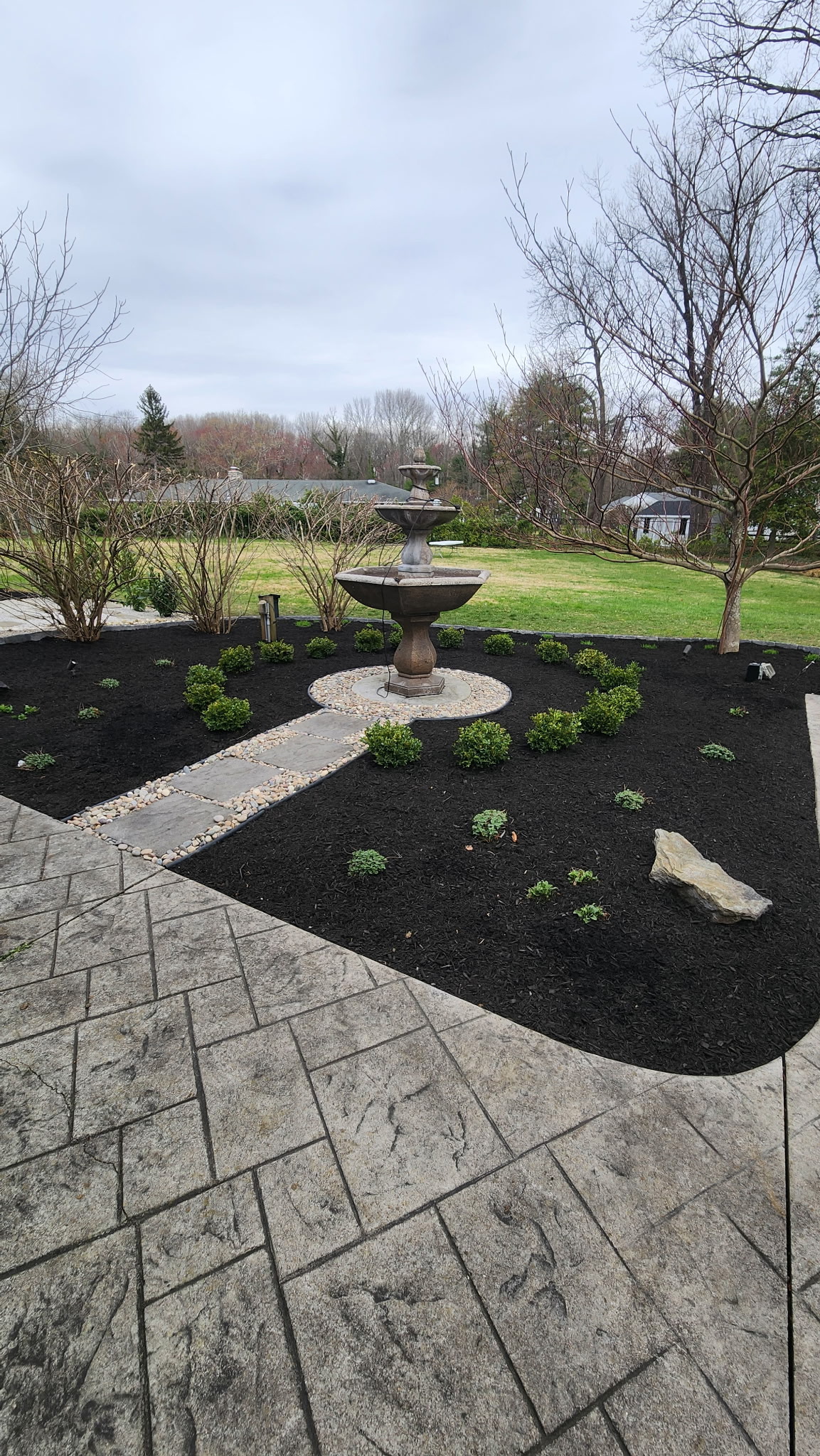 Stamped concrete patio with fountain and shrub plantings