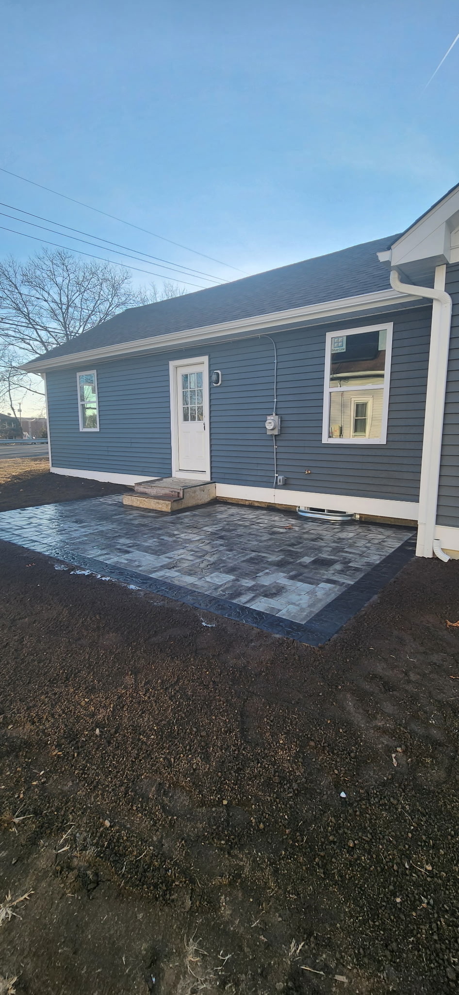 Paver patio installation behind residential home