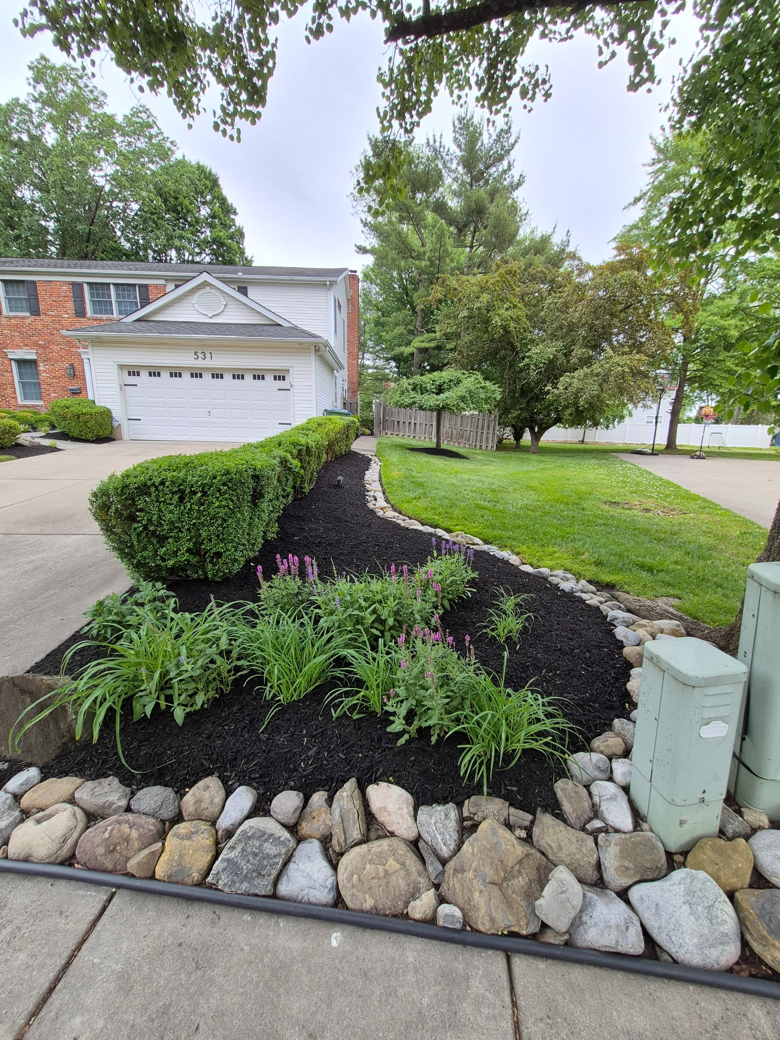 Driveway garden bed with stone border and perennial plants